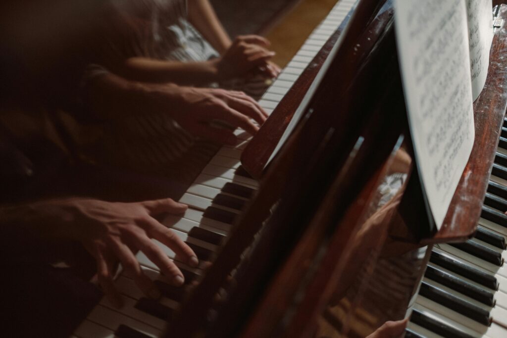 Intimate scene of hands playing a piano with visible sheet music, evoking a passion for music.